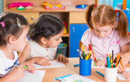 Három kisgyerek rajzol egy asztalnál